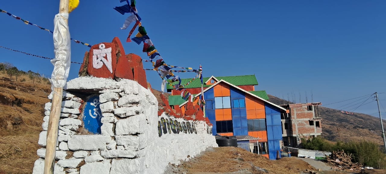 GreenHill Paradise hotel building with prayer flags and mani wall at Tumling